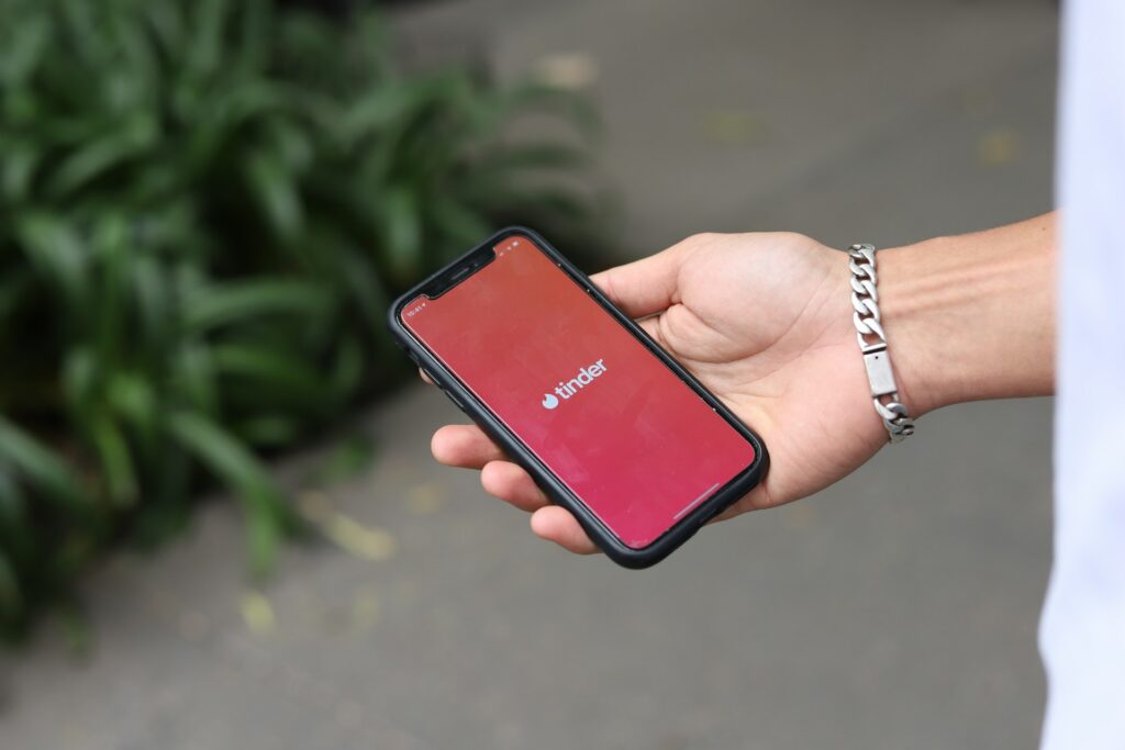 A person holding a phone with the Tinder loading screen visible.